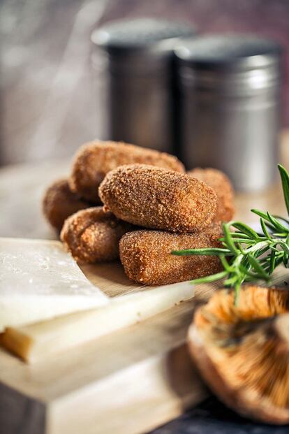 <p> <b> Ingredientes</b></p><p> Para 4 personas: 75 gramos de mantequilla, 50 gramos de aceite de oliva (más el de freír las croquetas), 1 cebolleta, 75 gramos de harina de trigo, 800 mililitros de leche entera, 200 gramos de queso Idiazabal, 250 gramos de níscalos, nuez moscada, 1 rama de romero fresco o seco, 2 huevos, pan rallado, sal y pimienta. </p><p> <b> Preparación</b></p><p> 1. Calentar la leche casi hasta que hierva y añadirle la rama de romero. Dejar en infusión hasta que la usemos en la bechamel. 2. Fundir en una olla la mantequilla con 50 gramos de aceite de oliva, y dorar en ella la cebolleta y los níscalos cortados en brunoise (tiras finas). 3. Cuando empiecen a coger color, añadir la harina y, a fuego medio-bajo y sin parar de remover, dejar que se tueste durante unos minutos. 4. Incorporar la leche –sin la rama de romero–, un poco de sal, pimienta y una pizca de nuez moscada molida. Trabajar la bechamel sin subir el fuego ni parar de remover hasta que espese. 5. En ese momento, sacarla del fuego y añadir el Idiazabal rallado fino. Remover hasta que se integre y dejar reposar, primero fuera de la nevera y después en frío. 6. Con las manos aceitadas, hacer bolas de unos 40 gramos con la masa y pasarlas por huevo y pan rallado. 7. Dejar reposar las croquetas ya hechas al menos un par de horas en la nevera (ayuda a que no se deshagan). 8. Freír en abundante aceite de oliva, pasar por un papel de cocina para eliminar la grasa sobrante y servir inmediatamente. </p>
