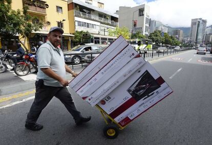 Un hombre lleva monitores en Caracas.