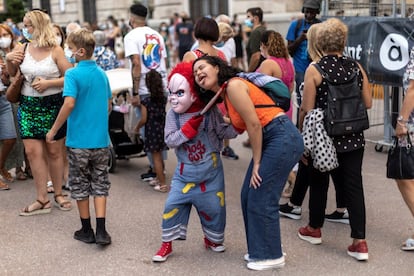 Una persona caracterizada del muñeco diabólico interactúa con una transeúnte durante la celebración de las Fallas en Valencia, este viernes.