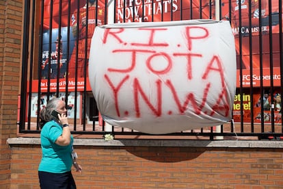 Una mujer pasa junto a una pancarta en la que se leen las siglas del 'Nunca Caminarás Solo', en homenaje al futbolista portugués del Liverpool Diogo Jota.
