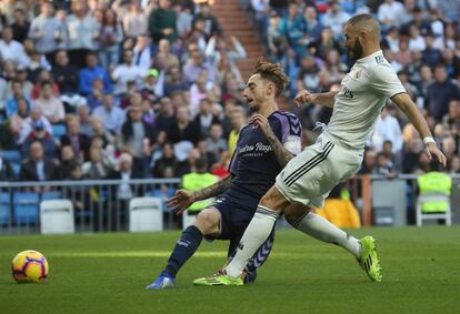 El delantero francés del Real Madrid, Karim Benzema (derecha), lucha por la pelota con el defensa del Real Valladolid Fernando Calero.