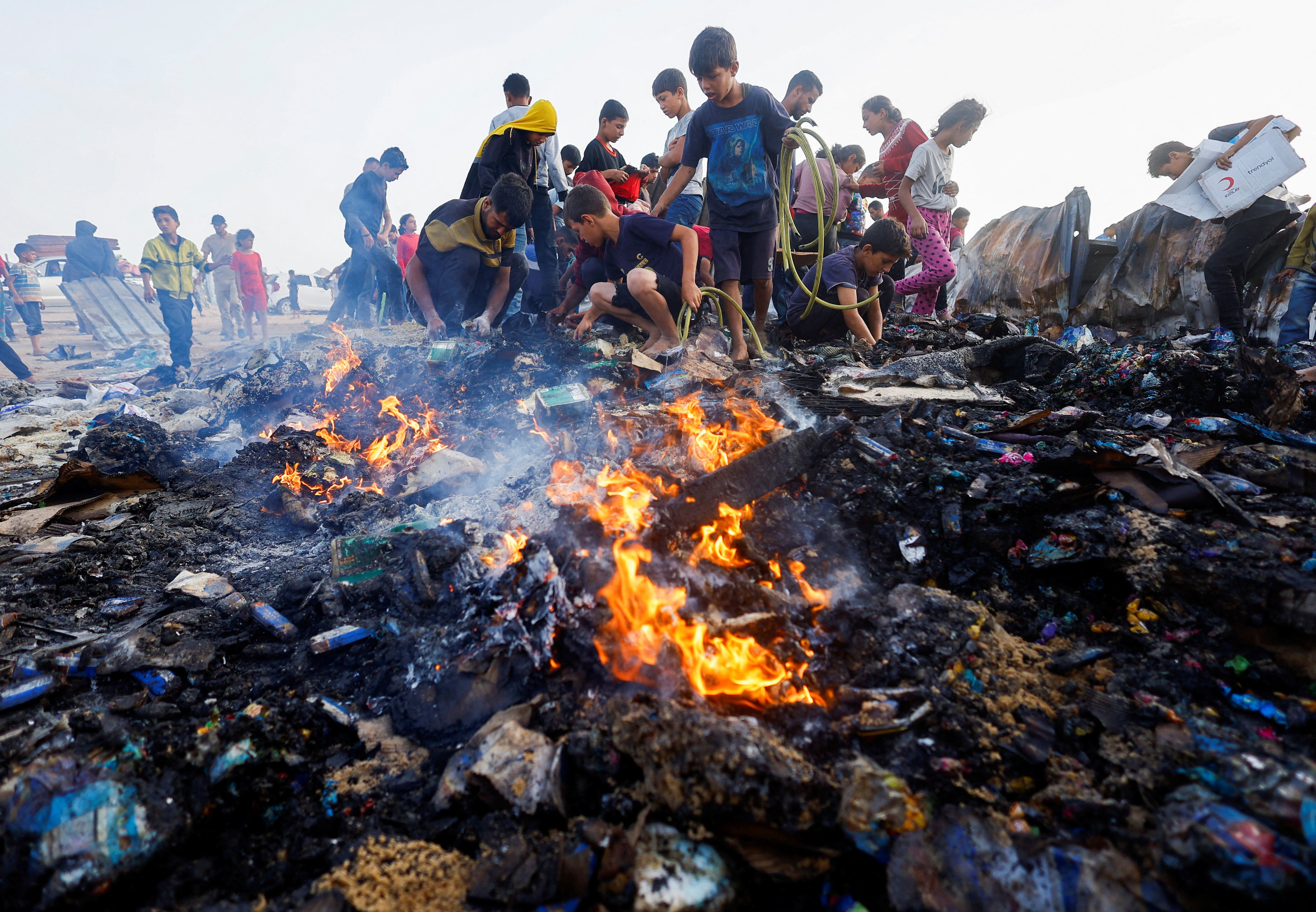 Un grupo de personas buscan comida entre los restos tras un ataque israelí sobre un campo de desplazados en Rafah, este lunes.  