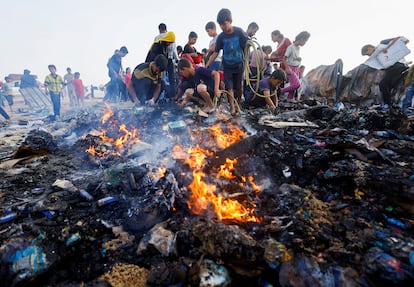 Varios jóvenes buscan comida entre las llamas provocadas por un bombardeo israelí sobre Rafah, en Gaza.