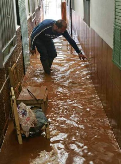 Un vecino achica agua en su casa, inundada por la tormenta.