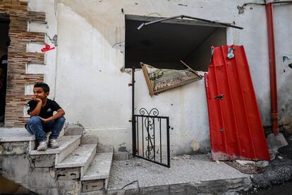 Un niño se sienta en la puerta de su casa destrozada por una explosión en Yenín, Cisjordania.