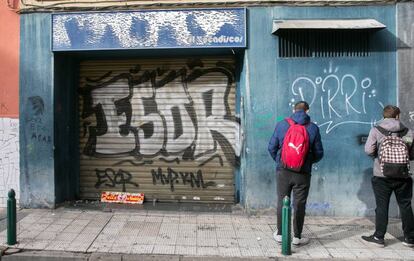 Unos jóvenes miran la puerta del bar donde fue agredido Víctor Laínez.