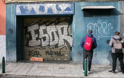 Unos j&oacute;venes miran la puerta del bar donde fue agredido V&iacute;ctor La&iacute;nez.