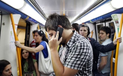 Un usuario habla por el móvil en un vagón del metro de Madrid.