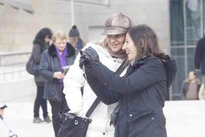 Una pareja de turistas aparecen a las puertas del Guggenheim Bilbao, en la fría mañana de ayer.