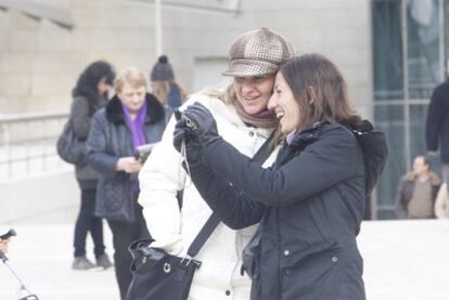 Una pareja de turistas aparecen a las puertas del Guggenheim Bilbao, en la fría mañana de ayer.