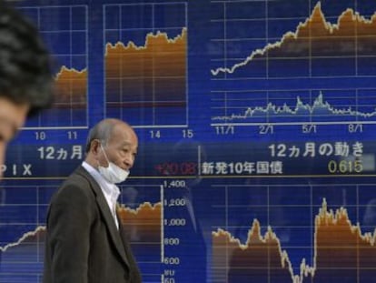 Dos hombres junto a una pantalla de la Bolsa en Tokio (Japón).