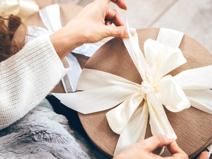 Plano detalle de una mujer abriendo un regalo con un gran lazo.