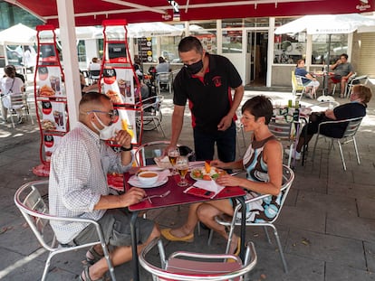 Un camarero sirve la comida a dos clientes en una terraza de Lleida.
