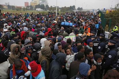 Migrantes esperan su turno para ser incorporados a las listas de evacuados del campamento de Calais (Francia).