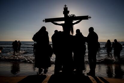 Cofrades llevan la talla del Cristo a la orilla de la playa en Valencia, este Viernes Santo. 