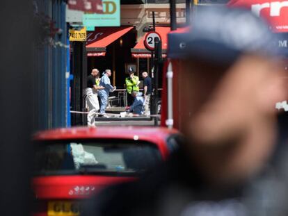 Police officers look for evidence at an attack site in London.