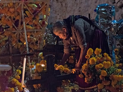 An Indigenous woman places a candle on the grave of a relative on Janitzio Island, Michoacán, Mexico.