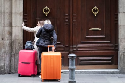 Dos personas con maletas accediendo a un edificio en Barcelona.
