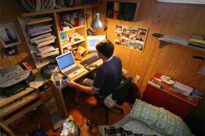 Un chico utiliza el ordenador en su habitación.