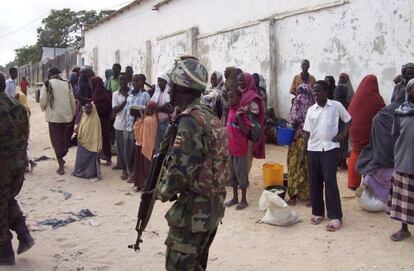 Un soldado de la Unión Africana en Somalia vigila a un grupo de somalíes.