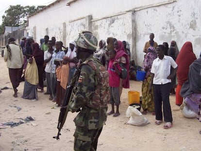 Un soldado de la Unión Africana en Somalia vigila a un grupo de somalíes.