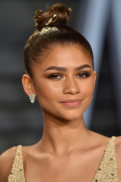 Zendaya, experta en atreverse con toda clase de peinados, sorprendió en la fiesta de Vanity Fair tras los Oscar con un pequeño moño decorado con hojas doradas.