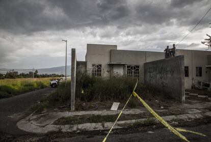 Jóvenes se asoman a observar las labores del forense en una fosa clandestina que fue descubierta en las periferias de la ciudad con cuatro cadáveres.