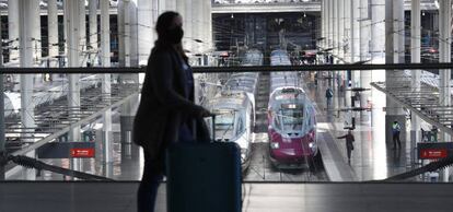 Una viajera transita por la estación Madrid Puerta de Atocha con los trenes de alta velocidad del AVE y Avlo de fondo.