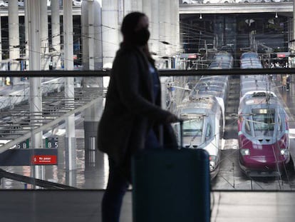 Una viajera transita por la estación Madrid Puerta de Atocha con los trenes de alta velocidad del AVE y Avlo de fondo.