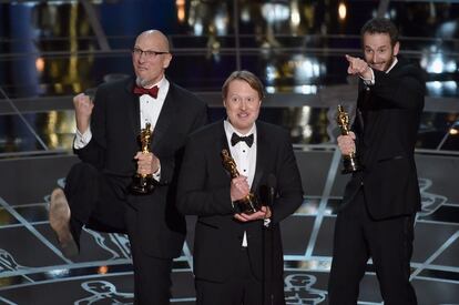 Los ganadores del Oscar a la mejor película animada, 'Big Hero 6 ', saludan exultantes sobre el escenario. De izquierda a derecha, Roy Conli, Don Hall y Chris Williams.