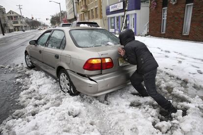 Una mujer empuja a un vehículo que se ha quedado atrapado entre la nieve en una calle de Ventnor, en el estado de New Jersey.