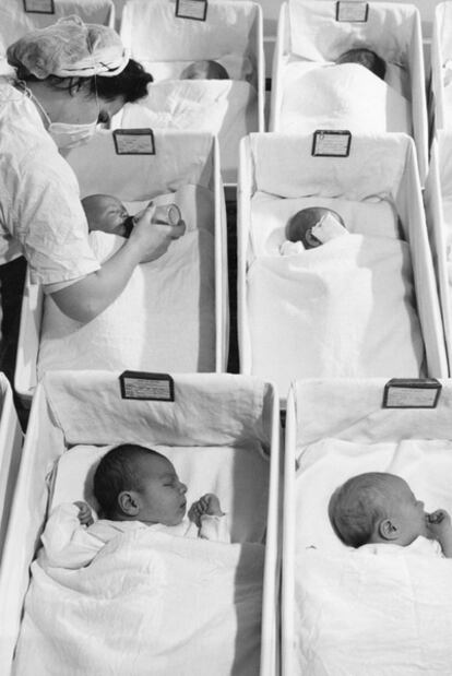 Una enfermera atiende a unos bebés en una sala para recién nacidos de un hospital.