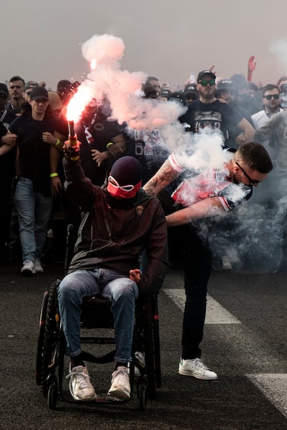 Un radical del PSG en silla de ruedas levanta una bengala en su camino hacia el Estadi Olímpic Lluís Companys de Barcelona.