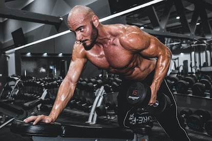 Usuario de un gimnasio haciendo ejercicios de musculación.