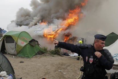 Un miembro de la policía francesa antidisturbios cerca de un área incendiada, en el campamento de Calais. 