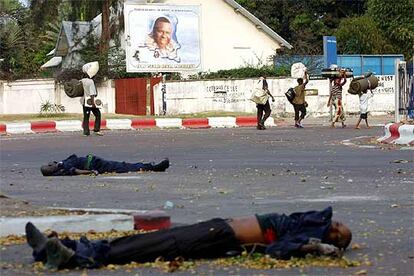 Un grupo de civiles pasa delante de dos hombres muertos en los enfrentamientos en Kinshasa.