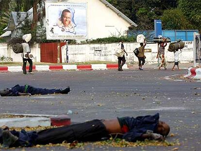 Un grupo de civiles pasa delante de dos hombres muertos en los enfrentamientos en Kinshasa.
