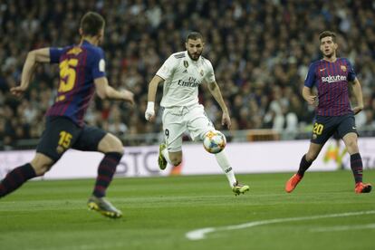 El delantero del Real Madrid, Karim Benzema, se lleva el balón ante dos jugadores del Barcelona.