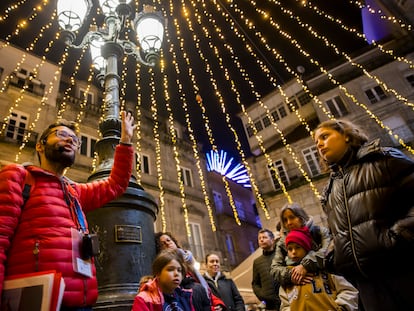 El guía José Manuel Pájaro acompaña a un grupo de turistas en el centro histórico de Vigo en un 'freetour' por las luces navideñas.