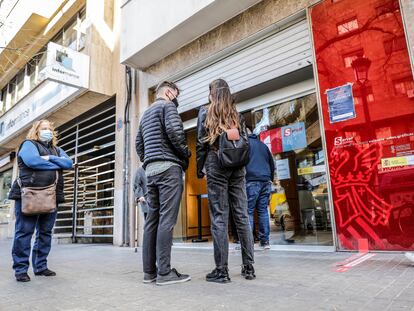 Varias personas hacen cola ante la puerta de oficina de empleo en València.