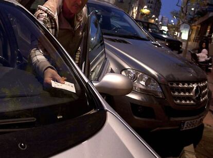 Un hombre pone en su coche el billete de zona azul en Almería.