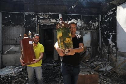 En la ciudad israelí de Lod, en la zona central, murieron un hombre de 52 años y su hija, de 16, al recibir el impacto directo de un proyectil en su casa. En la imagen, dos hombres sacan dos torás de una sinagoga incendiada tras disturbios nocturnos, este miércoles.