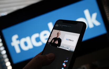 Una persona observa en su móvil cómo el fundador de Facebook, Mark Zuckerberg, presenta el logo de Meta.