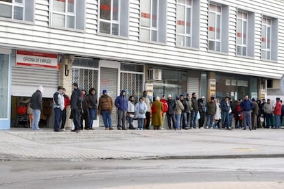 Varias personas forman una larga cola ante una oficina del INEM. 