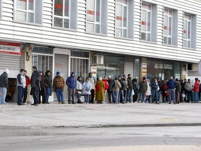 Varias personas forman una larga cola ante una oficina del INEM. 