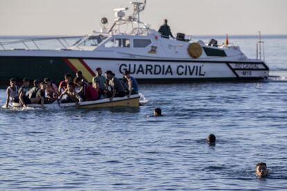 Un grupo de migrantes en barca y otros en el agua intentan llegar a la playa del Tarajal. Las fuerzas de seguridad y las unidades militares españolas desplegadas comenzaron este martes a aplicar la figura del rechazo en frontera para expulsar nada más llegar a los migrantes indocumentados, aunque la pasividad de los agentes marroquíes permitió durante horas que muchos volviesen a intentar inmediatamente cruzar.