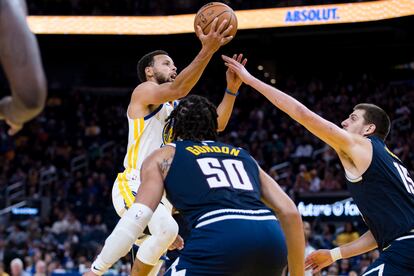 Stephen Curry, de los Golden State Warriors, trata de encestar frente a Nikola Jokic, de los Denver Nuggets, la semana pasada en un partido de pretemporada.