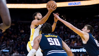 Stephen Curry, de los Golden State Warriors, trata de encestar frente a Nikola Jokic, de los Denver Nuggets, la semana pasada en un partido de pretemporada.