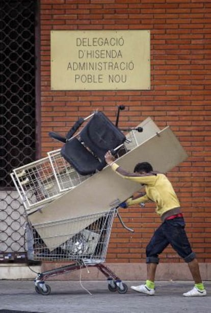 Un hombre acarrea un carrito con chatarra en el Poblenou.