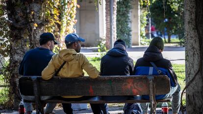 Un grupo de inmigrantes en el Jardín del Turia de Valencia durante un reparto de comida.